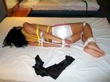 An archive girl tied, gagged and blind folded on a bed wearing only a white shiny nylon shorts (Pics)
