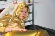 Pia posing in bed wearing golden shiny nylon rainwear and wings (Pics)