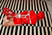 Marlin tied and gagged in red nylon shorts and red cagoule