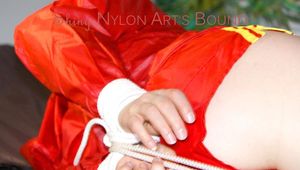 Lucy tied and gagged on a bed wearing a sexy red shiny nylon shorts and an oldschool blue rain jacket (Pics)