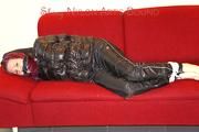 Mara tied and gagged on a sofa wearing a shiny black rain pants and down jacket (Pics) 