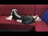 Samantha tied and gagged on a red sofa wearing a shiny black rainpants and a jacket (Video)