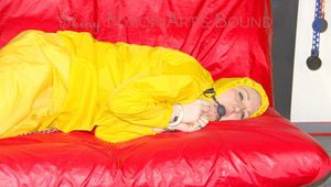 MARA ties, gagges and hoodes herself with cuffs and a ballgag on a sofa wearing sexy yellow rainwear (Pics)