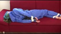 Mara tied and gagged on a sofa wearing sexy shiny rainwear in blue (Video)