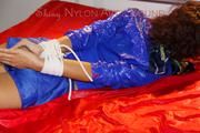 Lulu tied and gagged on a bed wearing a blue shiny nylon shorts and a blue rainjacket (Pics)