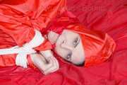 Destiny wearing a sexy red rain suit tied and gagged and hooded with ropes and a cloth gag on a bed (Pics)