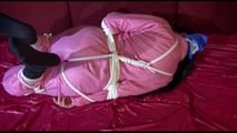 Lucy tied and gagged with ropes on a sofa wearing a pink oldschool shiny nylon down skibib freeing herself at the end (Video)