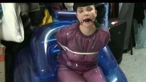 Video with Jill tied and gagged in a shiny purple semi transparent PVC suit