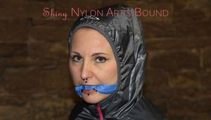 Mara tied and gagged on an barstool in an old cellar wearing a sexy lightblue shiny nylon shorts and a pink rainjacket (Pics)