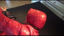 Pia tied, gagged and hooded on bed with a bar wearing y sexy black shiny nylon down pants and a red downjacket (Video)