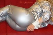 Sophie tied and gagged on the sofa wearing a shiny silver PVC sauna suit (Pics)
