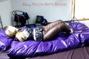 Samantha tied and gagged on bed wearing shiny downpants in brown and a black downjacket (Pics)