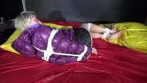 Watching sexy Sonnja wearing a black shiny nylon down skirt and a purple downjacket being tied and gagged with ropes and a ballgag on a bed (Video)