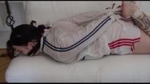 Jill tied and gagged on a white sofa wearing a white nylon shorts and a white rain jacket (Video)