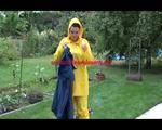 Jill wearing a shiny yellow rainpants and rain jacket pulls over a raincoat and playing with water our of the water hose (Video)