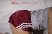 Sexy Sandra wearing a very shiny bordeaux red shiny nylon shorts and a grey top posing for you on a sofa (Pics)