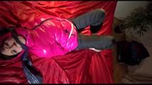 Mara tied, gagged and hooded on a bed wearing a supersexy black rain pants and a pink down jacket (Video)