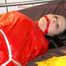 Lucy tied and gagged on a bed wearing a sexy red shiny nylon shorts and an oldschool blue rain jacket (Pics)