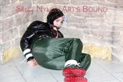 Jill tied, gagged and hooded on a cellar floor wearing a shiny green rain pants and a shiny black down jacket (Pics)