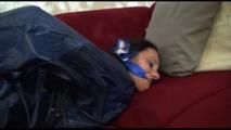 Lucy tied and gagged on a red sofa wearing a sexy red shiny nylon shorts and a blue rain jacket (Video)