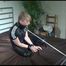 Mara tied and gagged on bed with a bar and a neckband wearing a very hot black shiny nylon jumpsuit (Video)
