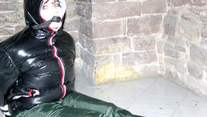 Jill tied, gagged and hooded on a cellar floor wearing a shiny green rain pants and a shiny black down jacket (Pics)