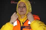 Watching Mara wearing a black shiny nylon rain pants putting on a yellow down jacket and red rubber boots as well as a lifevest (Pics)