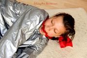 Alina tied and gagged in a shiny silver PVC saunasuit