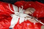Nina tied and gagged in a shiny red PVC suit