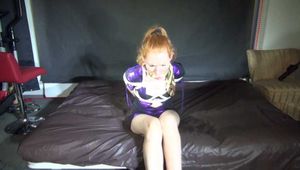 Red haired Woman bound and gagged in a shiny purple wetlook Dress