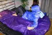 Pia tied, gagged and hooded with cuffs and chains on a bed wearing a sexy black rain pants and a blue down jacket (Pics)