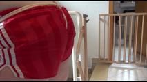 Jill tied and gagged on a stairrail wearing a sexy shiny red shorts with shadow stripes and a top (Video)