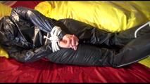 Lucy tied and gagged on bed wearing a sexy black shiny nylon pants and a black rain jacket (Video)