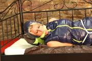 Pia tied, gagged and hooded in a princess bed wearing a sexy black rain pants and a sexy darkblue down vest (Pics)