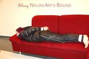 Mara tied and gagged on a sofa wearing a shiny black rain pants and down jacket (Pics) 