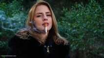 Absolutely stunning lady is smoking two long cigarettes in the park