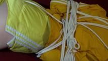 Lucy tied and gagged on a red sofa wearing a sexy yellow shiny nylon shorts and a yellow rain jacket (Video)