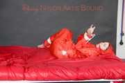 Destiny wearing a sexy red rain suit tied and gagged and hooded with ropes and a cloth gag on a bed (Pics)