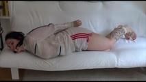 Jill tied and gagged on a white sofa wearing a white nylon shorts and a white rain jacket (Video)