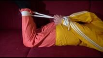 Lucy tied, gagged and hooded on a red sofa wearing a sexy orange shiny nylon pants and a yellow rain jacket (Video)