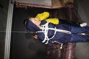 Sandra tied by Stella both wearing shiny nylon rainwear