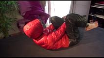 Pia tied, gagged and hooded on bed with a bar wearing y sexy black shiny nylon down pants and a red downjacket (Video)
