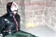 Jill tied, gagged and hooded on a cellar floor wearing a shiny green rain pants and a shiny black down jacket (Pics)