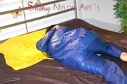 Lucy putting on an blue agu rain pants and rain jacket and lolling on bed in shiny nylon bed cloths (Pics)