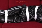 Alina tied and gagged in a shiny black PVC sauna suit