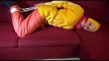 Lucy tied, gagged and hooded on a red sofa wearing a sexy orange shiny nylon pants and a yellow rain jacket (Video)