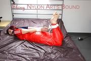 Mara tied and gagged on bed wearing a sexy shiny nylon catsuit in red (Pics)
