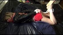 Pia tied and gagged on a bed wearing a sexy red adidas sprinter and a black/orange rain jacket (Video)