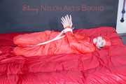 Destiny wearing a sexy red rain suit tied and gagged and hooded with ropes and a cloth gag on a bed (Pics)