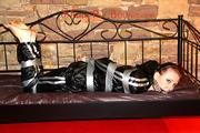 Mara tied with tape and gagged on a princess bed in an old cellar wearing an black sauna suit (Pics)